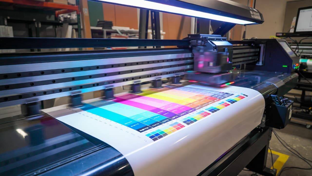 UV printer performing color calibration on flatbed substrate with CMYK test chart